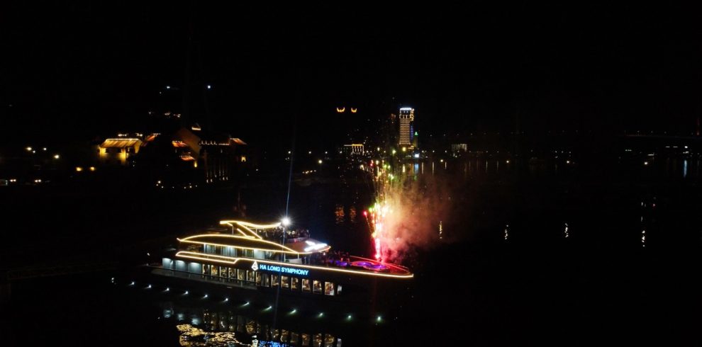 Nighttime Halong Bay cruise with fireworks and illuminated boat scene, perfect for travel enthusiast.