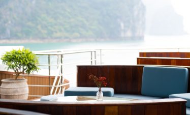 Stunning view from a cruise balcony overlooking Halong Bay's emerald waters and limestone karsts.