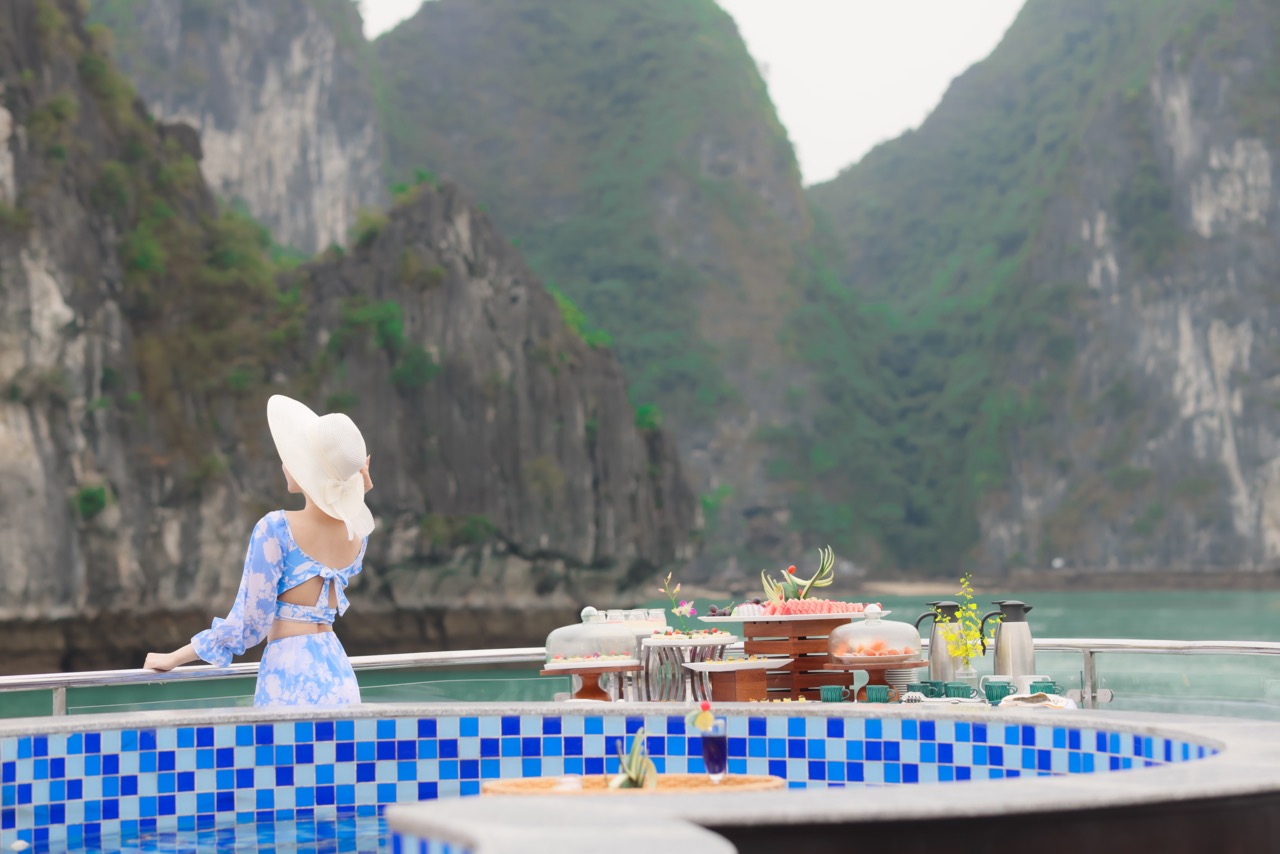 Halong Bay cruise balcony with dining setup, showcasing stunning limestone karsts and tranquil water.
