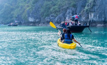 Kayaking in Halong Bay with stunning limestone karsts and emerald waters.