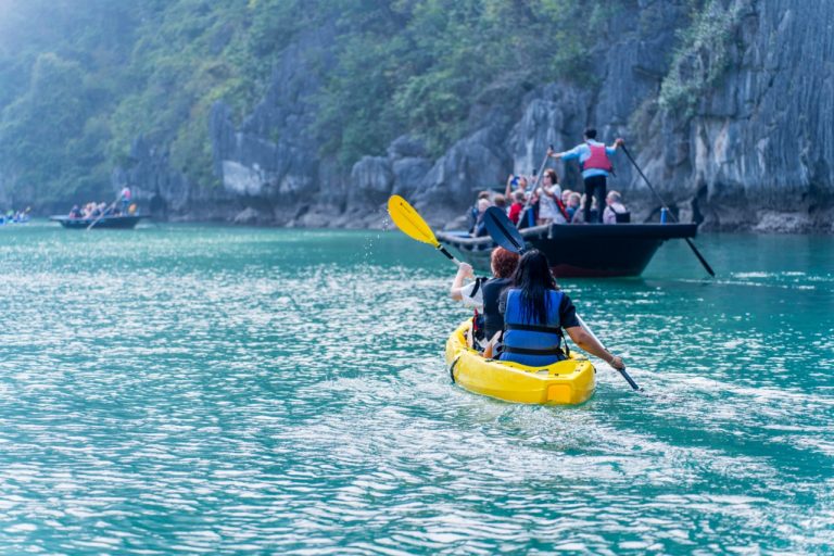 Kayaking in Halong Bay with stunning limestone karsts and emerald waters.