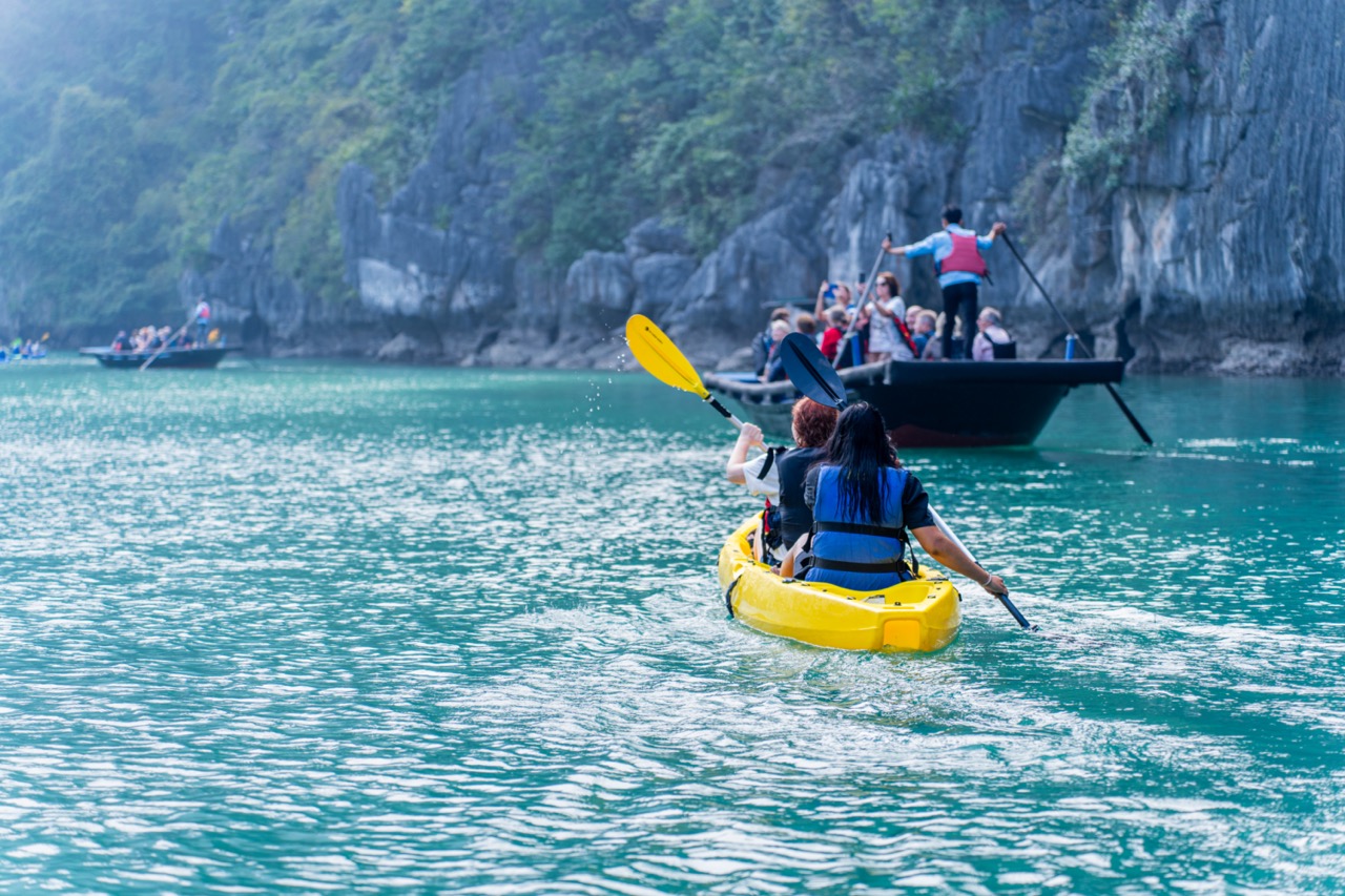 Kayaking in Halong Bay with stunning limestone karsts and emerald waters.