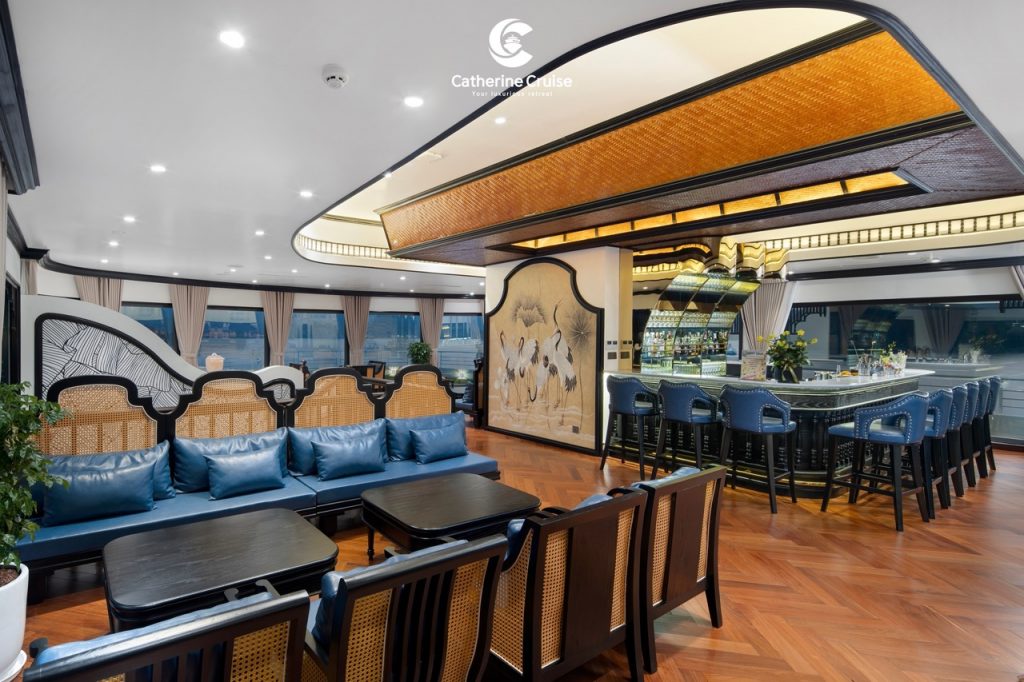 Elegant cruise lounge interior with bar, seating, and panoramic windows.