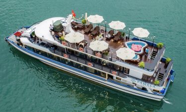 Aerial view of a luxurious Halong Bay cruise ship with rooftop lounge, private deck, and scenic wate.