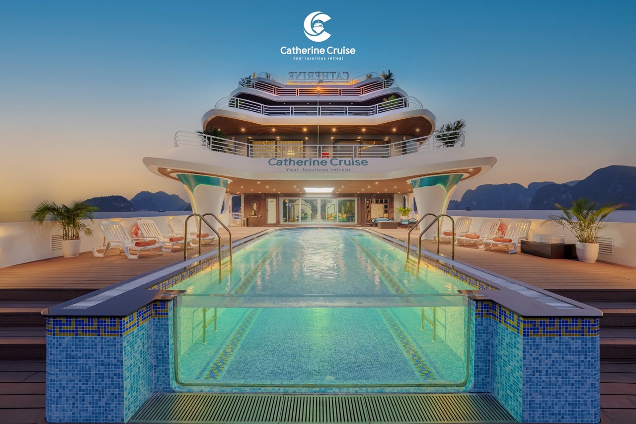 Luxury cruise ship deck with swimming pool and mountain views at sunset.