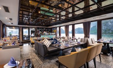 Luxurious cruise lounge with panoramic views of Halong Bay, elegant seating, and stylish decor.
