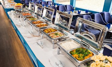 Stunning view of a buffet meal on a Halong Bay cruise with scenic water and mountain backdrop.