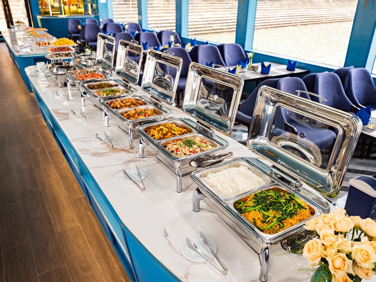 Stunning view of a buffet meal on a Halong Bay cruise with scenic water and mountain backdrop.