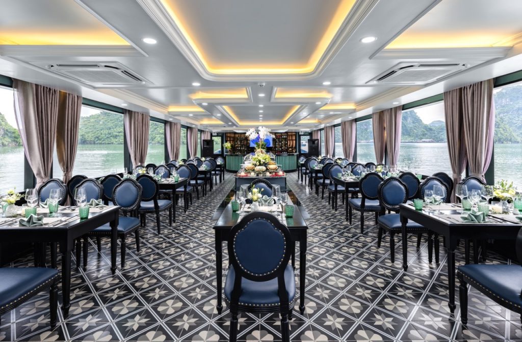 Elegant cruise dining area with panoramic views of Halong Bay, perfect for a luxurious sailing exper.