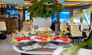 Beautiful dining setup on Heritage Cruise in Halong Bay with fresh fruit and floral decorations.
