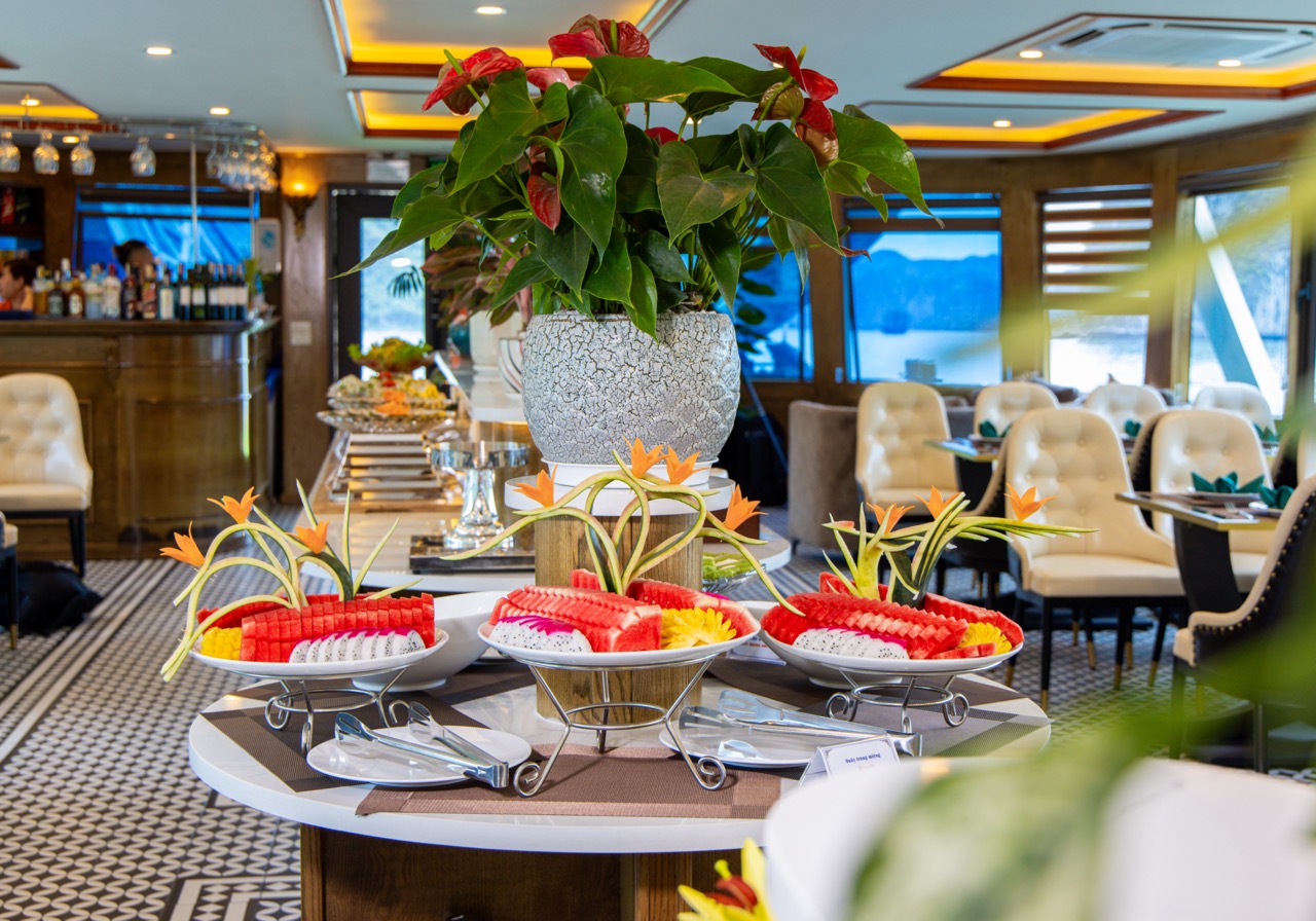 Beautiful dining setup on Heritage Cruise in Halong Bay with fresh fruit and floral decorations.