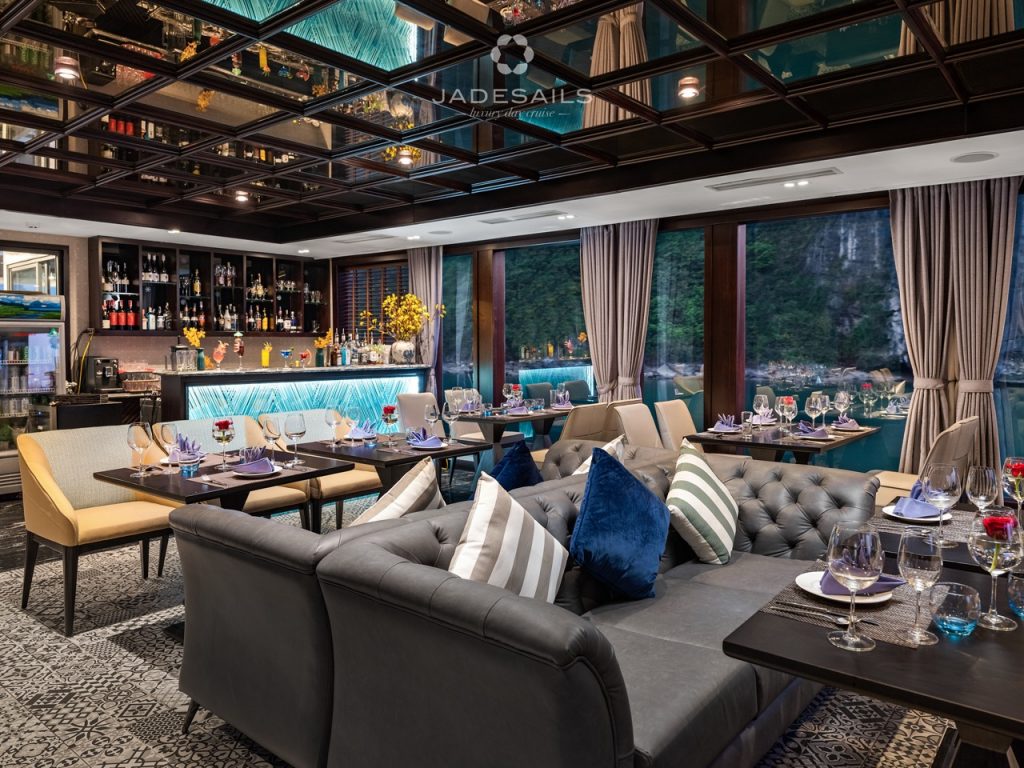 Elegant cruise lounge with panoramic views of Halong Bay, featuring stylish seating and sophisticate.