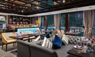 Elegant cruise lounge with panoramic views of Halong Bay, featuring stylish seating and sophisticate.