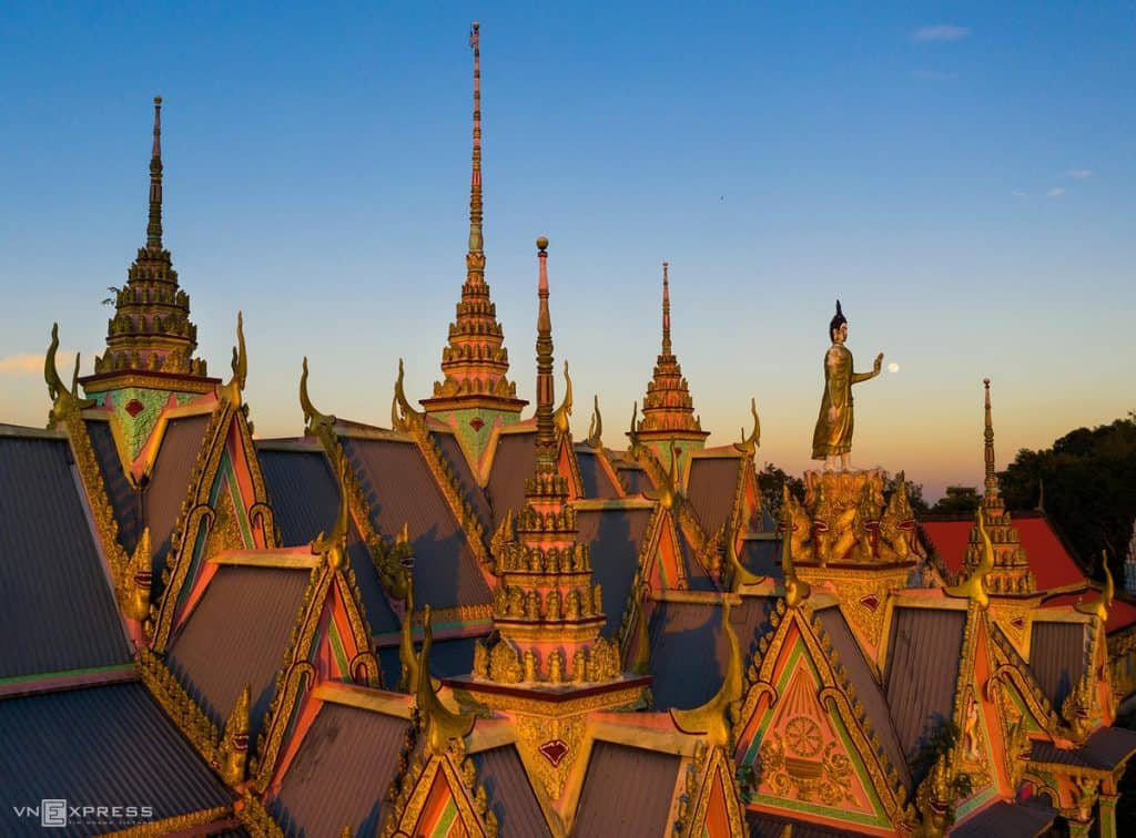 Temple complex with ornate rooftops and golden spires at sunset, showcasing traditional architecture.
