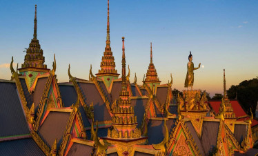 Temple complex with ornate rooftops and golden spires at sunset, showcasing traditional architecture.