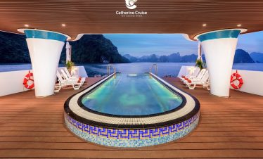 Luxury cruise ship pool with scenic limestone islands in the background.