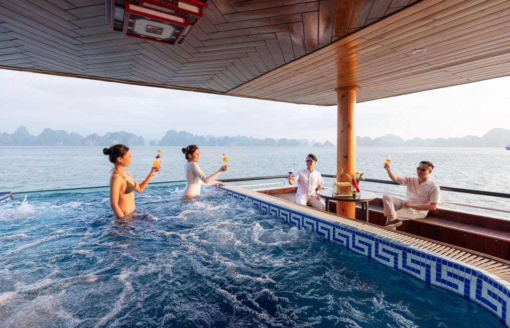 Relaxing cruise balcony with friends enjoying drinks in Halong Bay, stunning seascape view, vibrant.