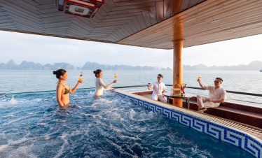 Relaxing cruise balcony with friends enjoying drinks in Halong Bay, stunning seascape view, vibrant.