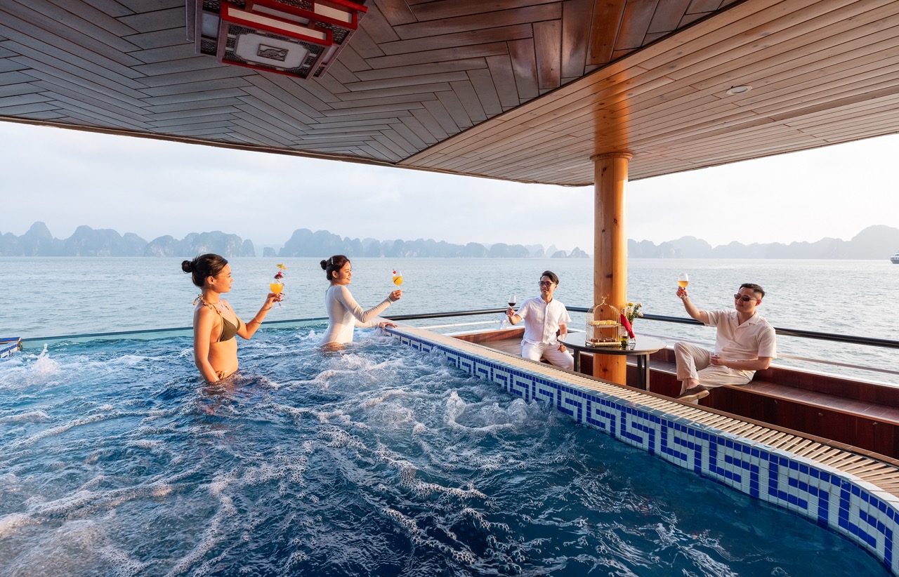 Relaxing cruise balcony with friends enjoying drinks in Halong Bay, stunning seascape view, vibrant.