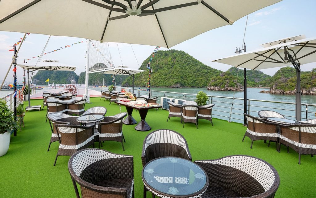 Stunning view of Halong Bay from a cruise balcony with seating and umbrellas, perfect for relaxing a.