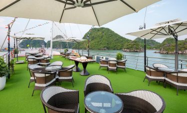 Stunning view of Halong Bay from a cruise balcony with seating and umbrellas, perfect for relaxing a.