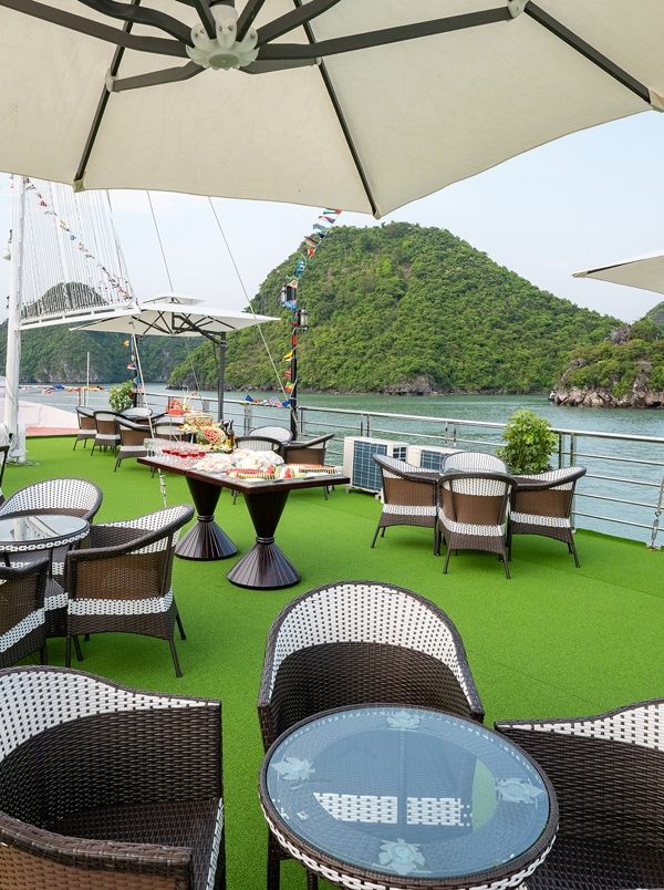 Stunning view of Halong Bay from a cruise balcony with seating and umbrellas, perfect for relaxing a.