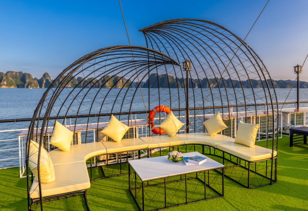 Relaxing outdoor lounge on Heritage Cruise with stunning views of Halong Bay's limestone karsts.