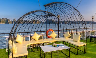 Relaxing outdoor lounge on Heritage Cruise with stunning views of Halong Bay's limestone karsts.