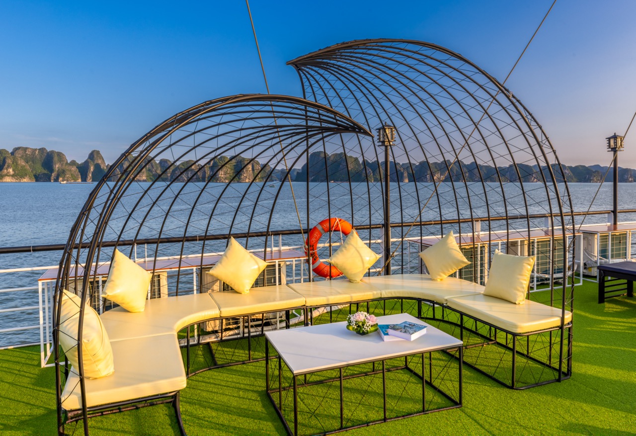 Relaxing outdoor lounge on Heritage Cruise with stunning views of Halong Bay's limestone karsts.