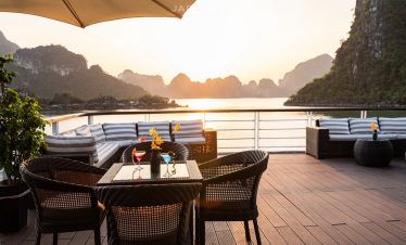 Scenic sunset over Halong Bay from cruise deck with outdoor seating, limestone karsts, and tranquil.