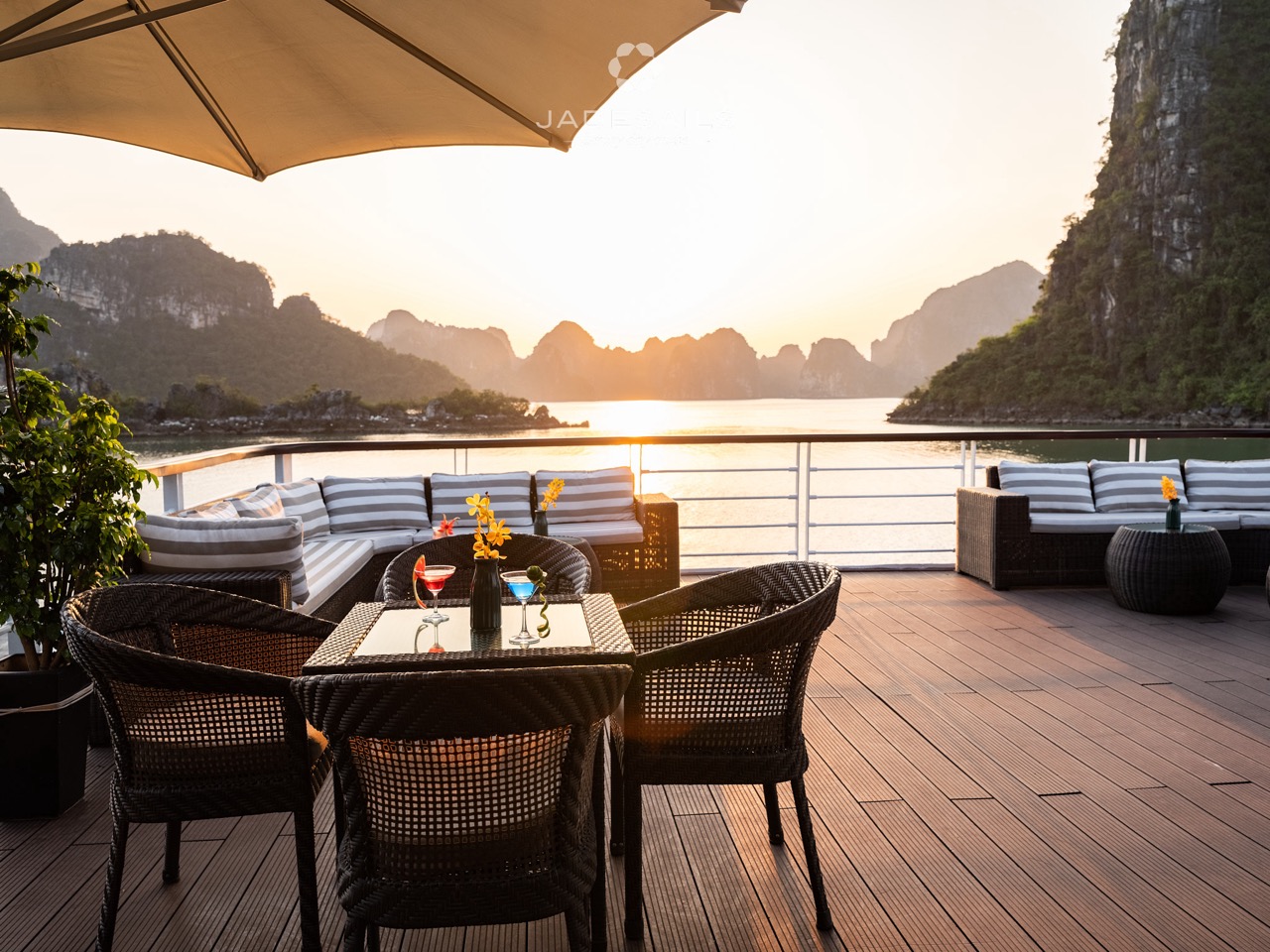 Scenic sunset over Halong Bay from cruise deck with outdoor seating, limestone karsts, and tranquil.