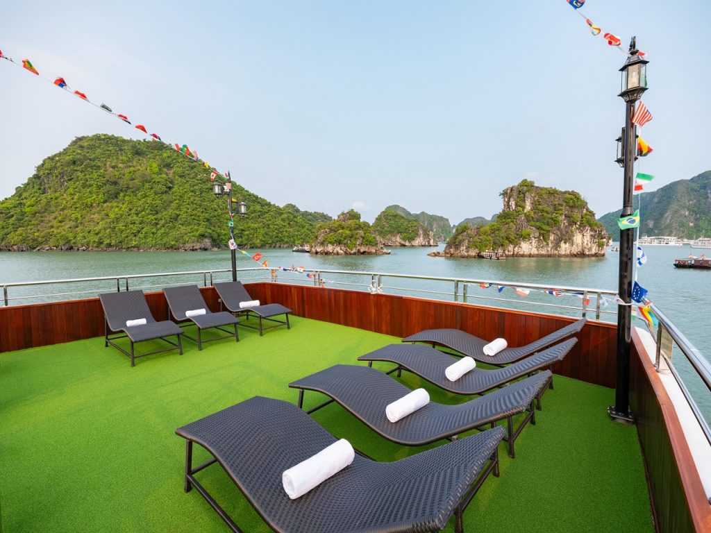 Scenic view of Halong Bay with lounge chairs on the cruise deck, lush islands, and calm waters, perf.