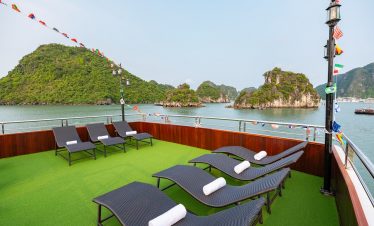 Scenic view of Halong Bay with lounge chairs on the cruise deck, lush islands, and calm waters, perf.