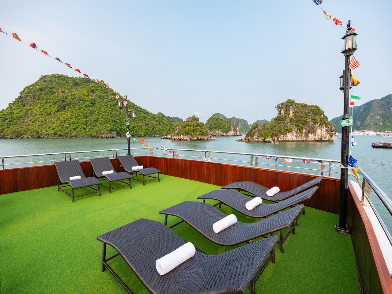 Scenic view of Halong Bay with lounge chairs on the cruise deck, lush islands, and calm waters, perf.