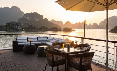 Relaxing cruise balcony with scenic views of Halong Bay at sunset, perfect for a memorable travel ex.