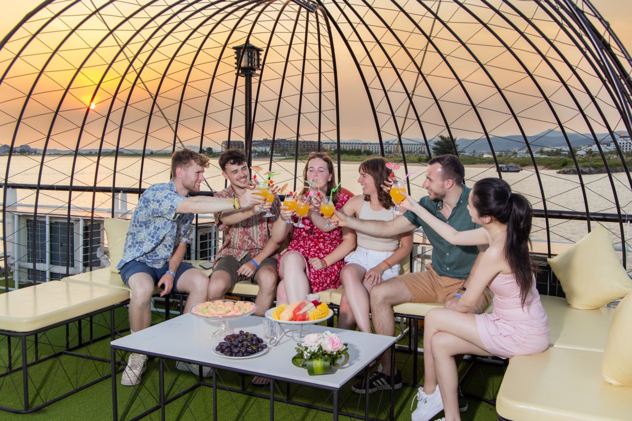 Enjoy a lively sunset celebration on a cruise balcony in Halong Bay with friends.