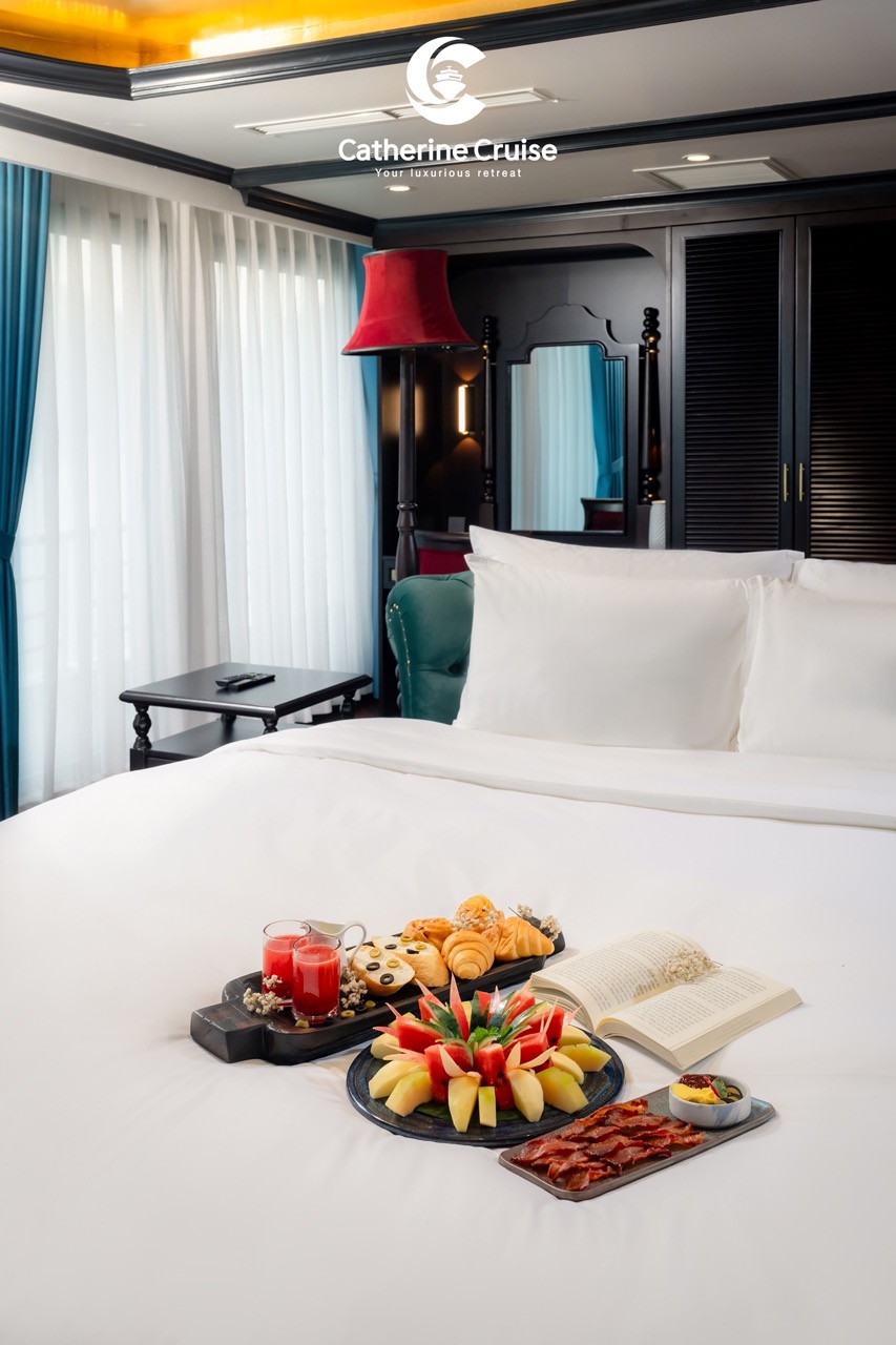 Luxurious cruise cabin with breakfast and fruit on bed for a relaxing vacation.