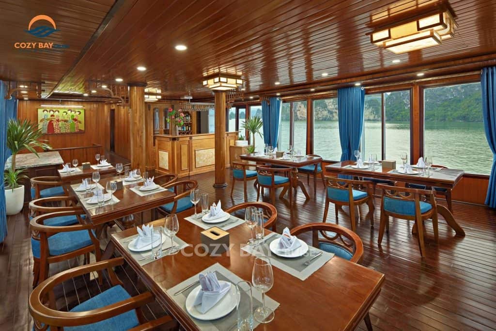 Halong Bay cruise dining area with elegant wooden decor and scenic water views.