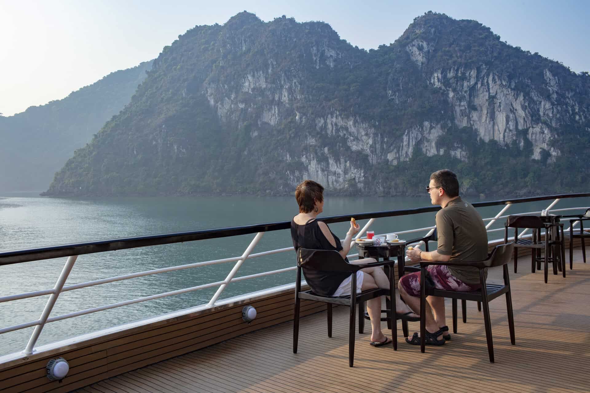 Scenic view of a couple enjoying a luxurious cruise on Halong Bay's emerald waters.