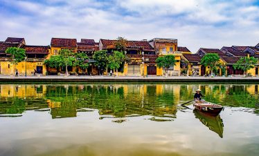 Hoi An riverside scene with traditional houses and boat.