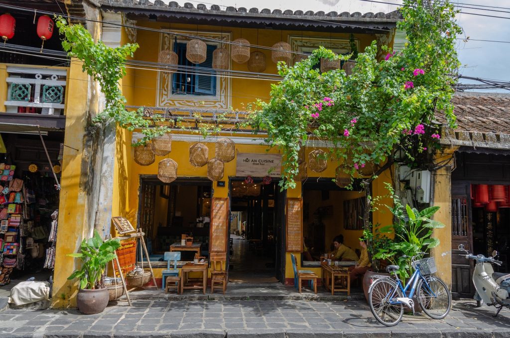Hoi An Heritage Town street scene with traditional architecture and vibrant greenery.