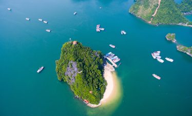 Stunning aerial view of a lush island surrounded by emerald waters in Halong Bay.