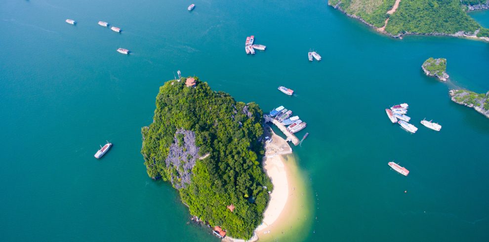 Stunning aerial view of a lush island surrounded by emerald waters in Halong Bay.