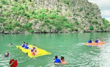 Halong Bay kayaking scene with tourists exploring stunning limestone karsts.