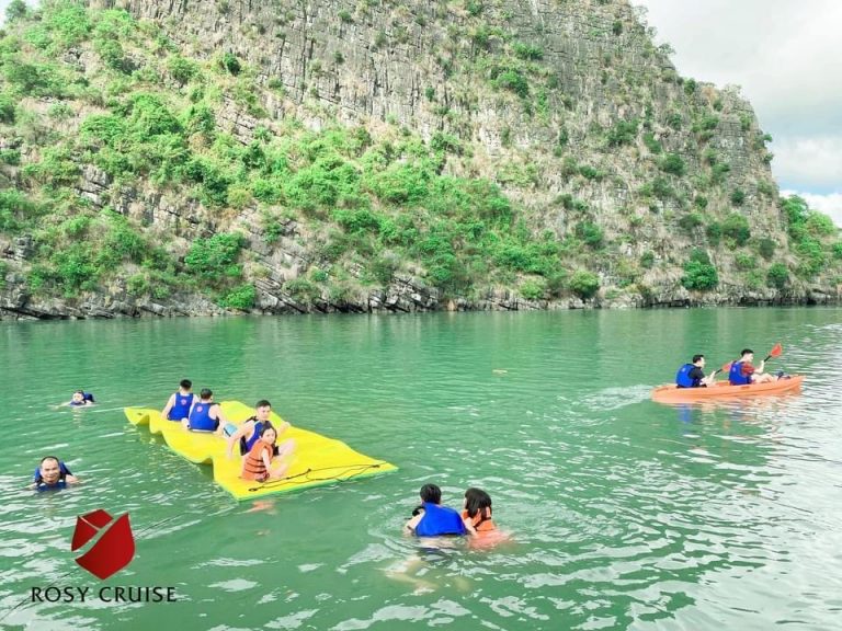 Halong Bay kayaking scene with tourists exploring stunning limestone karsts.