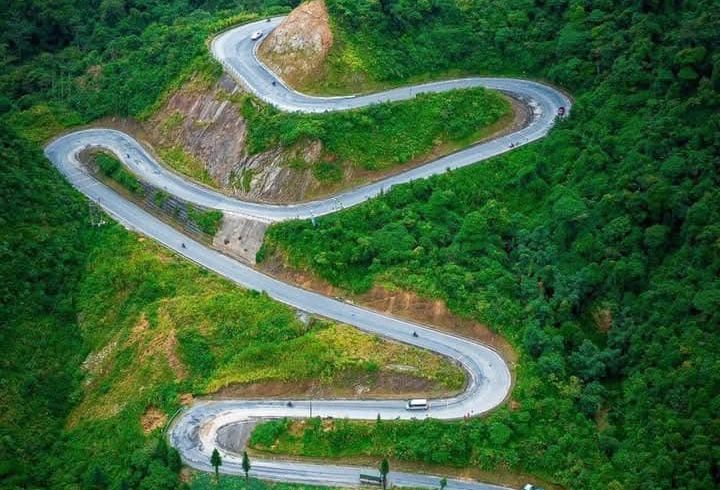 Scenic mountain road in Ha Giang with lush greenery and sharp curves, perfect for adventurous travel.