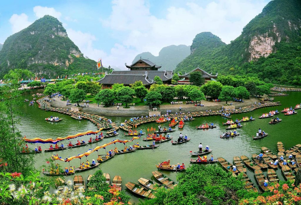 Stunning view of boat-filled river surrounded by lush green mountains in Ninh Binh.