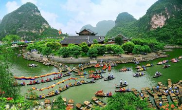 Stunning view of boat-filled river surrounded by lush green mountains in Ninh Binh.