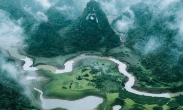 Stunning aerial view of lush green mountains and winding rivers in Vietnam, perfect for adventure an.