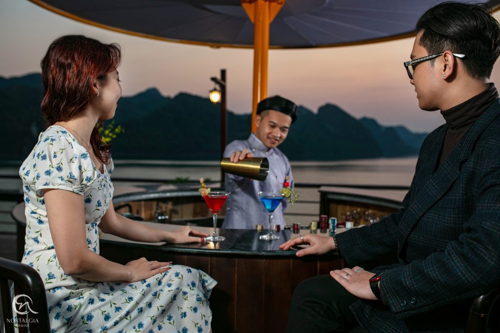 Elegant scene of couple enjoying a romantic evening on a Lan Ha Bay cruise balcony at sunset, showca.